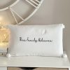 'This family believes' white pompom cushion